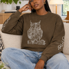 A brown crewneck sweatshirt featuring a white line art graphic of an owl on the chest, with white script text printed on both sleeves, displayed against a solid white background.