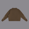 A dark brown cropped sweatshirt shown from the back, featuring long sleeves with small white graphic prints on the upper arms, set against a plain white background.