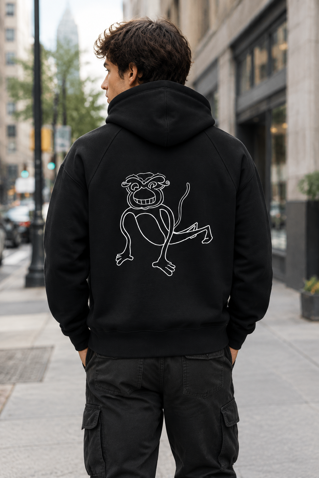 A black hooded sweatshirt shown from the back, featuring a white line art graphic of a cartoon monkey on the center back, set against a plain white background.